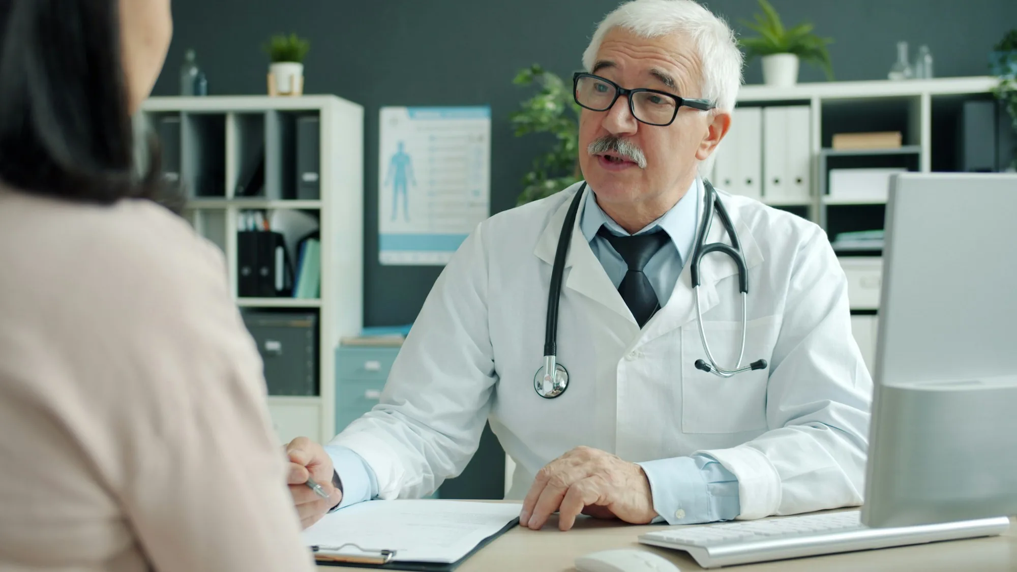 A doctor talking with a patient across a consulting room desk